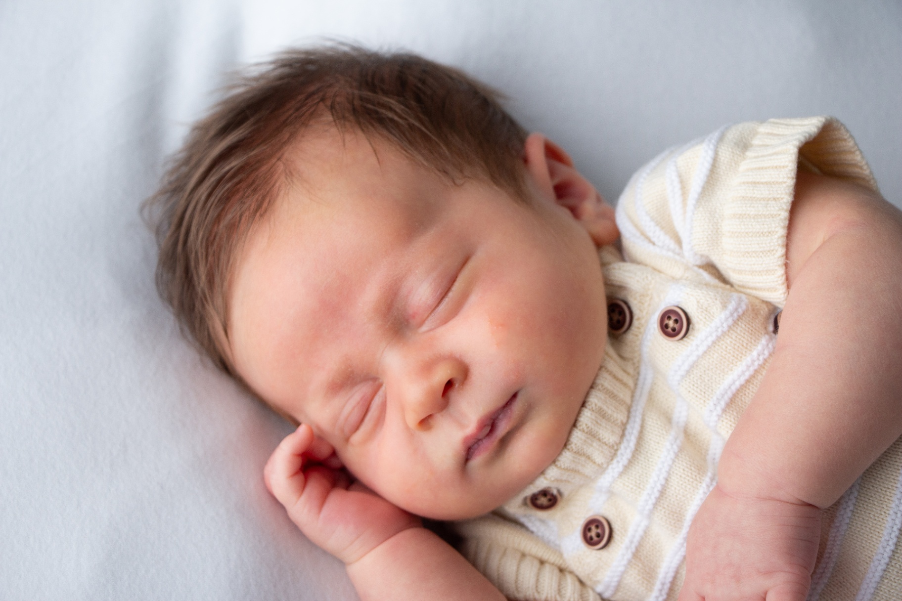 Close-up of a newborn in an ivory knit outfit